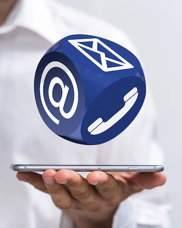 Imagen de una mano sosteniendo una tablet con un icono azul flotante que representa el correo electrónico y el teléfono.